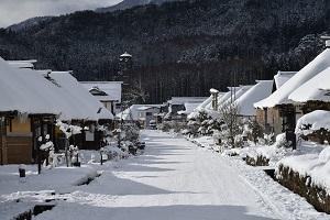 雪に覆われた大内宿の町並みの写真（通りの両脇に家が並んでいる）