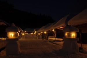 夜の大内宿雪まつりの写真001（雪に覆われた大内宿の町並みが雪灯籠の暖かい光に照らされている）