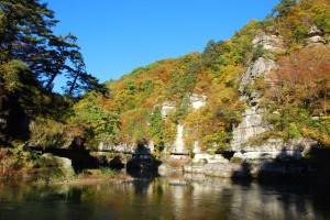秋の塔のへつりの写真（横）001（川から見上げる岩肌の上のほうは紅葉した木で覆われている）